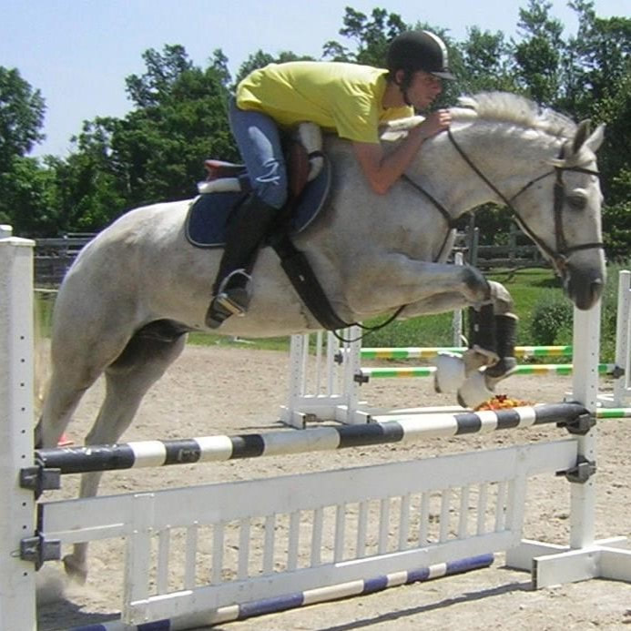 student and his horse  jumping a fence in a lesson