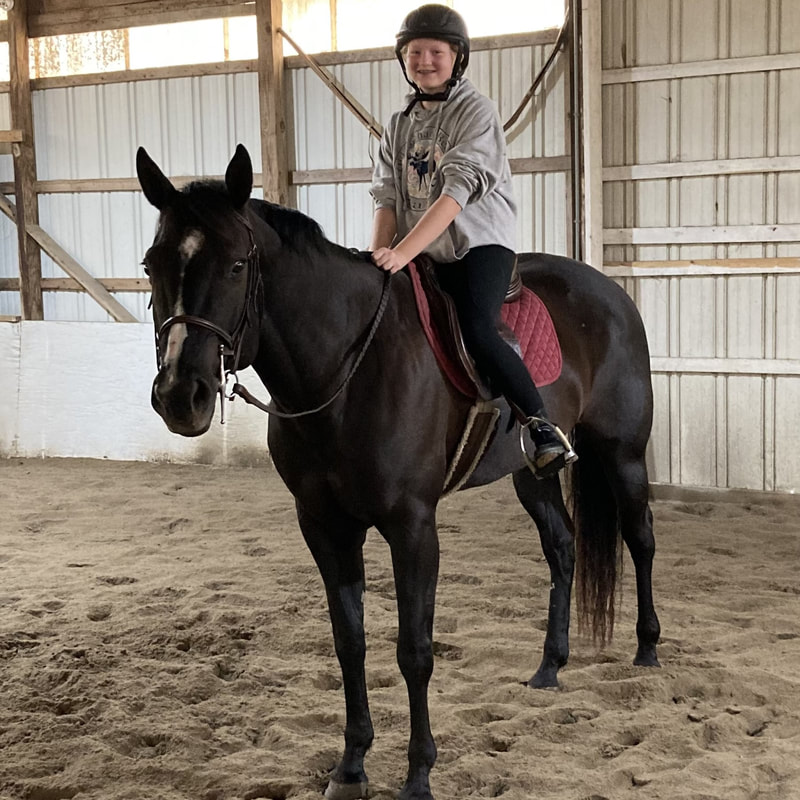 smiling student on her horse during a riding lesson