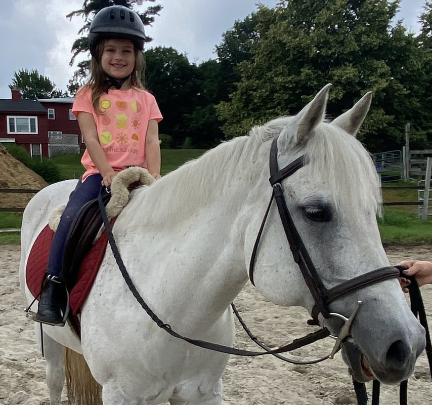 smiling student on her horse during a riding lesson